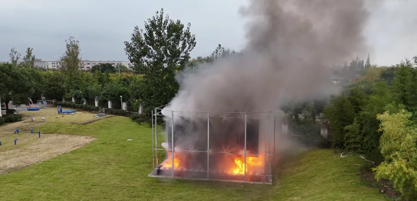 Water mist discharging around a transformer test assembly with an oil fire burning at the base